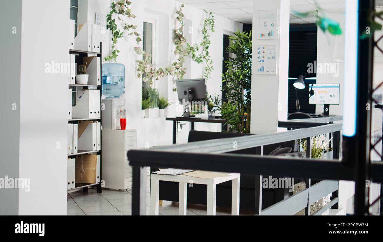 Piano aperto dell'azienda con scrivanie e forniture per ufficio utilizzate per il reparto aziendale degli unicorno. Spazio di coworking vuoto pieno di decorazioni e postazioni di lavoro, edificio professionale. Foto Stock