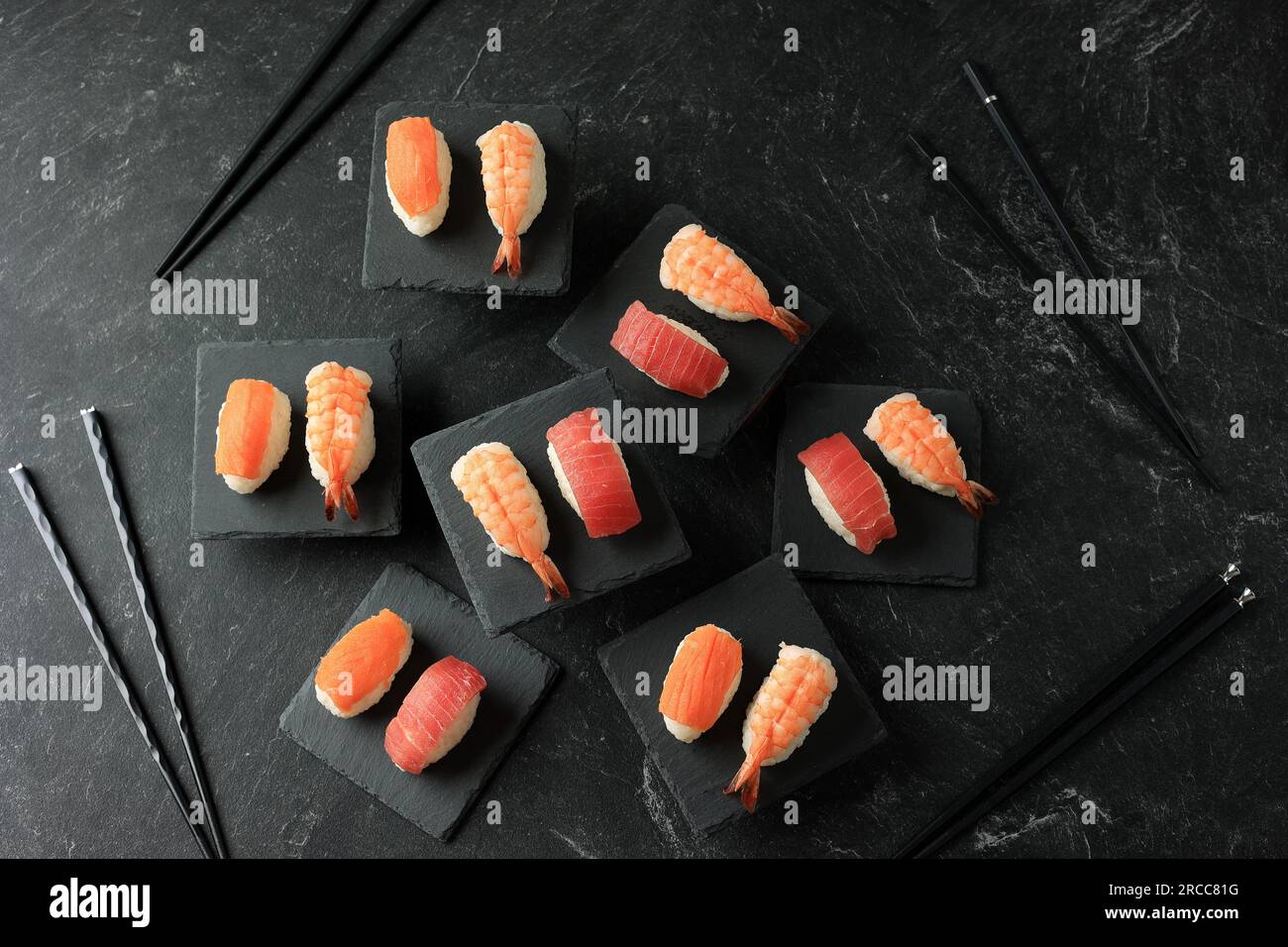 Cibo giapponese, sushi di salmone, sushi al tonno e riso Nigiri ai gamberi. Vista dall'alto sulla tavola ardesia nera Foto Stock