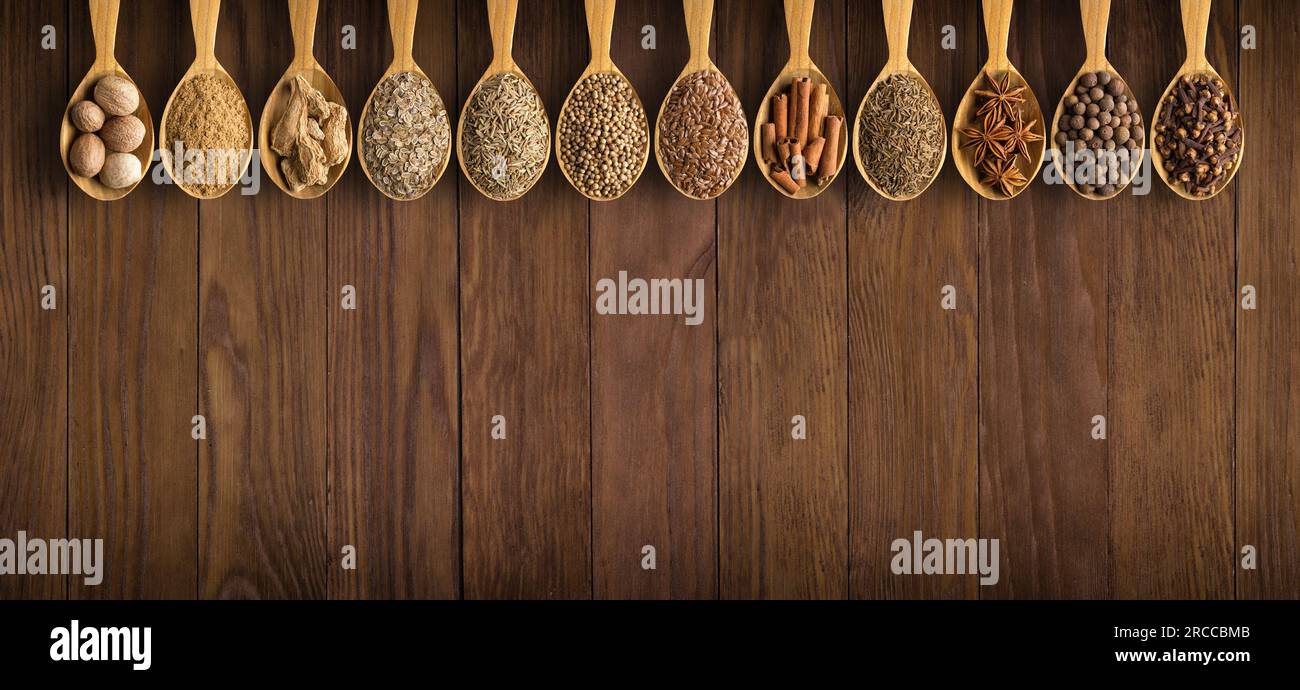 Raccogliete spezie indiane in cucchiai su uno sfondo di legno Foto Stock