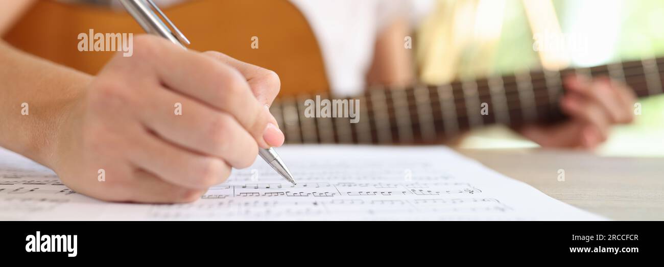 Primo piano di una compositrice femminile che scrive note musicali in quaderno. Foto Stock