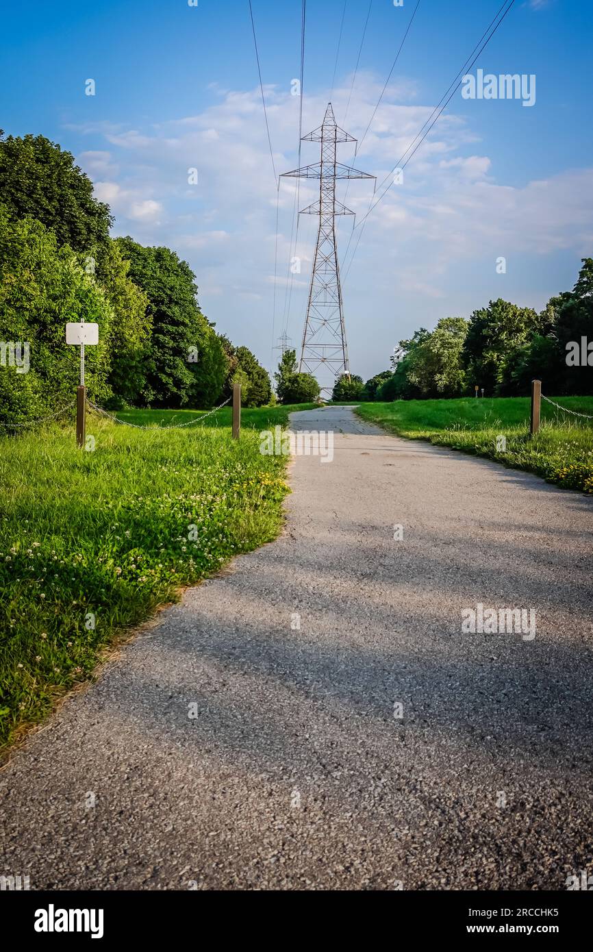 un sentiero a piedi che conduce a una torre di trasmissione dell'energia elettrica all'esterno in un parco Foto Stock