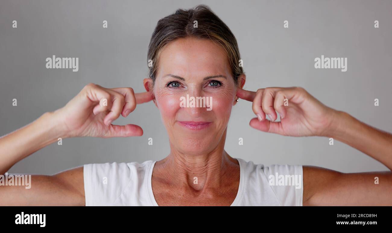 Donna stressata che copre le orecchie. Forte pressione del rumore Foto Stock