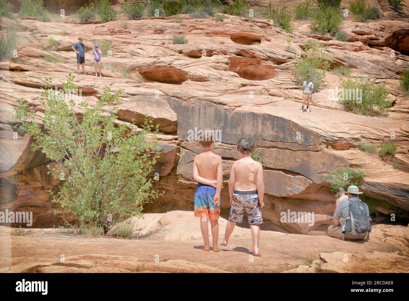 Due giovani ragazzi, dal retro, contemplano il salto sulla scogliera vicino a Moab UT Foto Stock