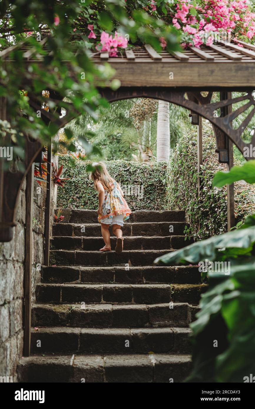 La giovane ragazza sale le scale in pietra nel lussureggiante giardino tropicale di St Kitts Foto Stock