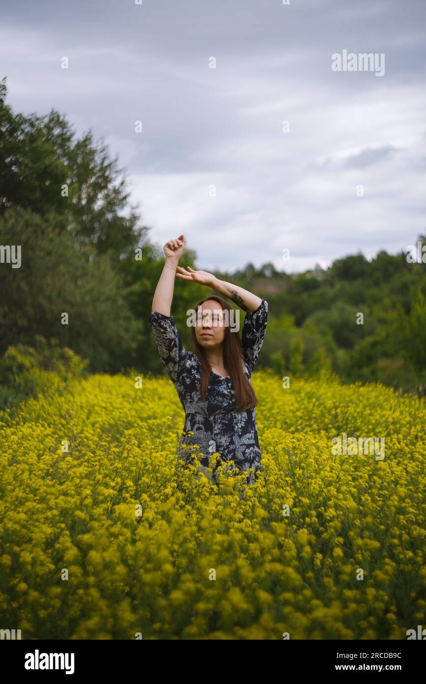 La donna in vestito sta in fiori gialli Foto Stock