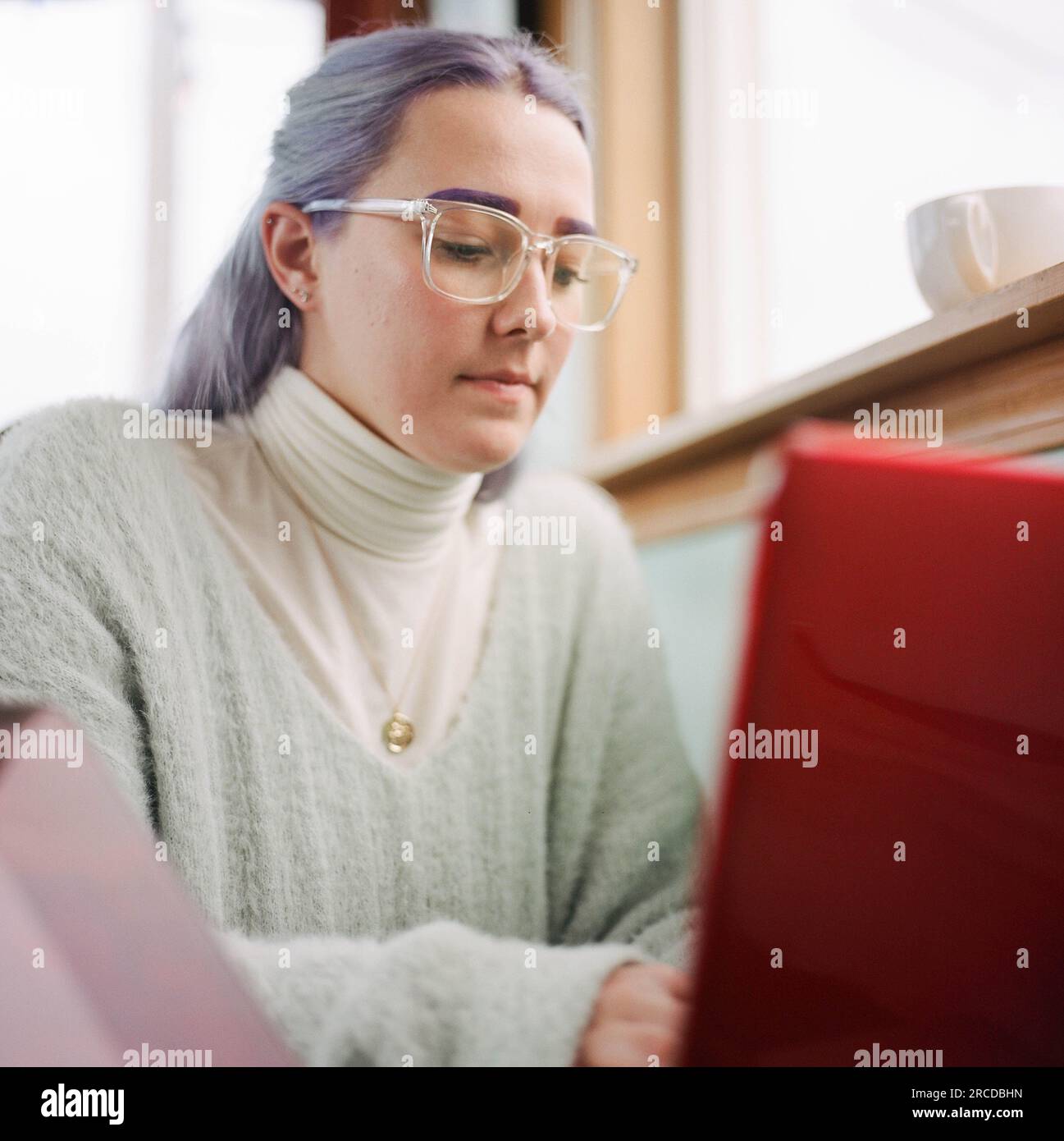Studente universitario con capelli viola e sopracciglia sul suo laptop Foto Stock