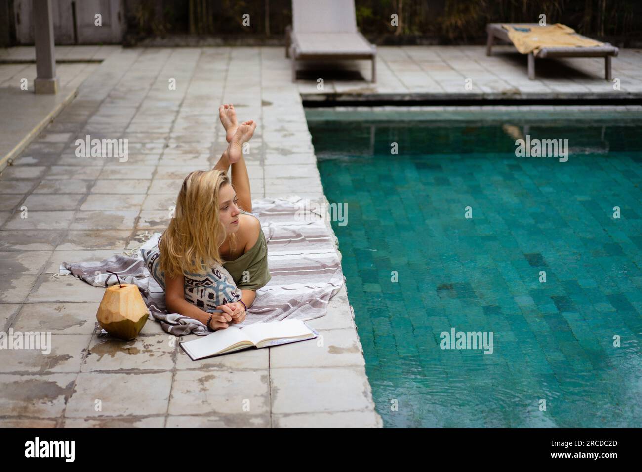 Una giovane donna passa del tempo vicino alla piscina, scrivendo un diario. Foto Stock