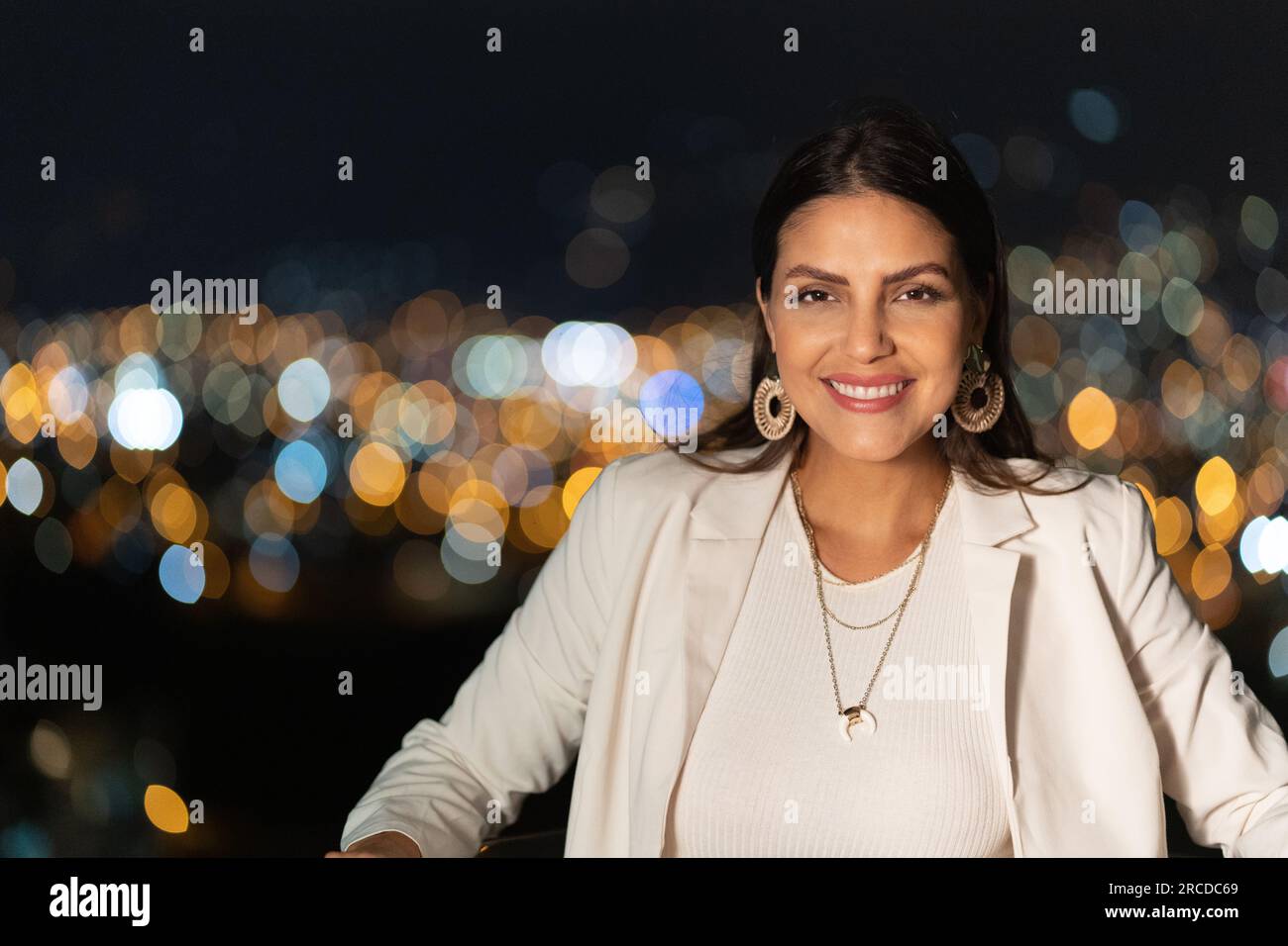 Ritratto di una bella donna con le luci della città sfocano lo sfondo Foto Stock