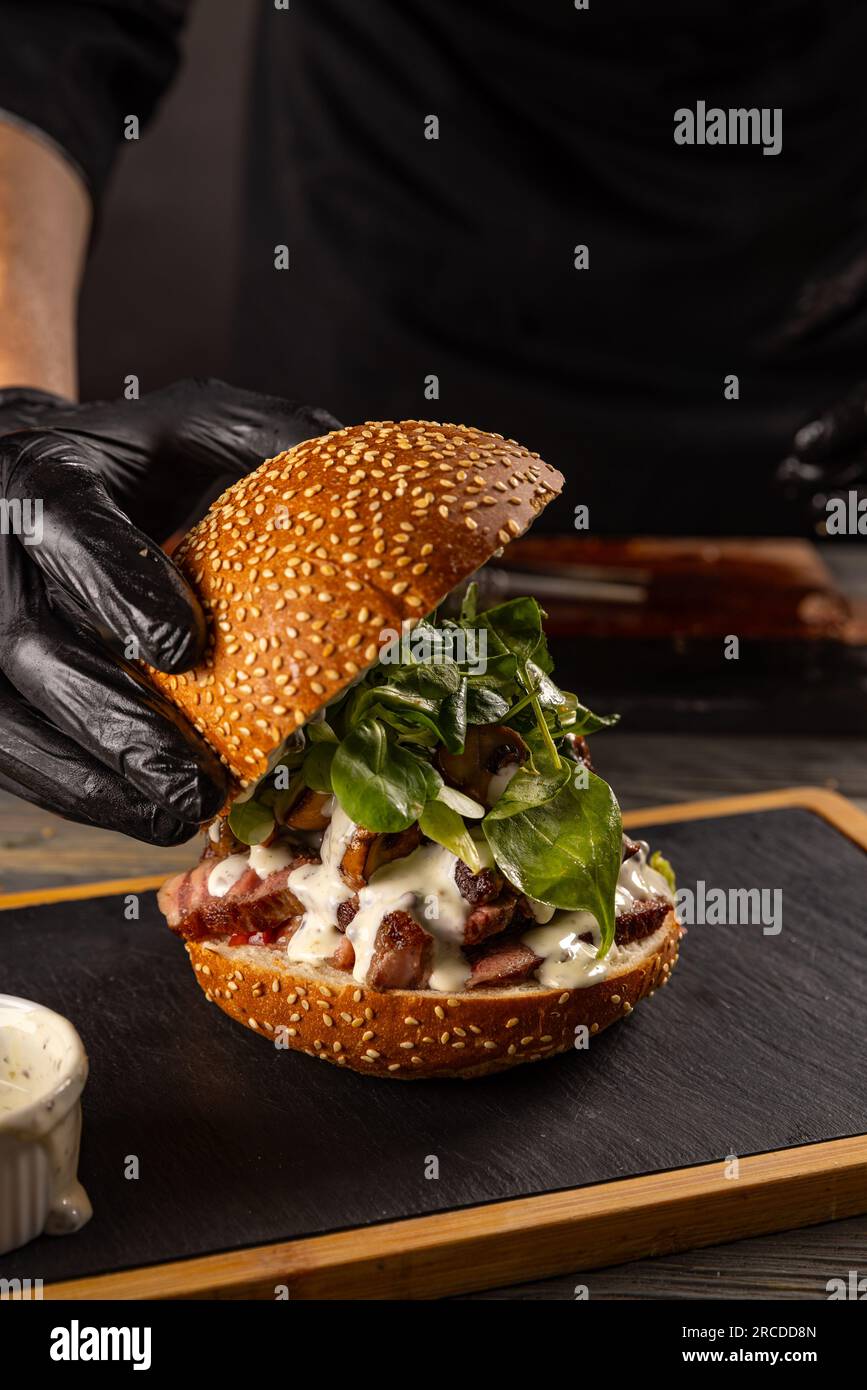 Primo piano della mano dello chef che prepara un delizioso hamburger di bistecca Foto Stock