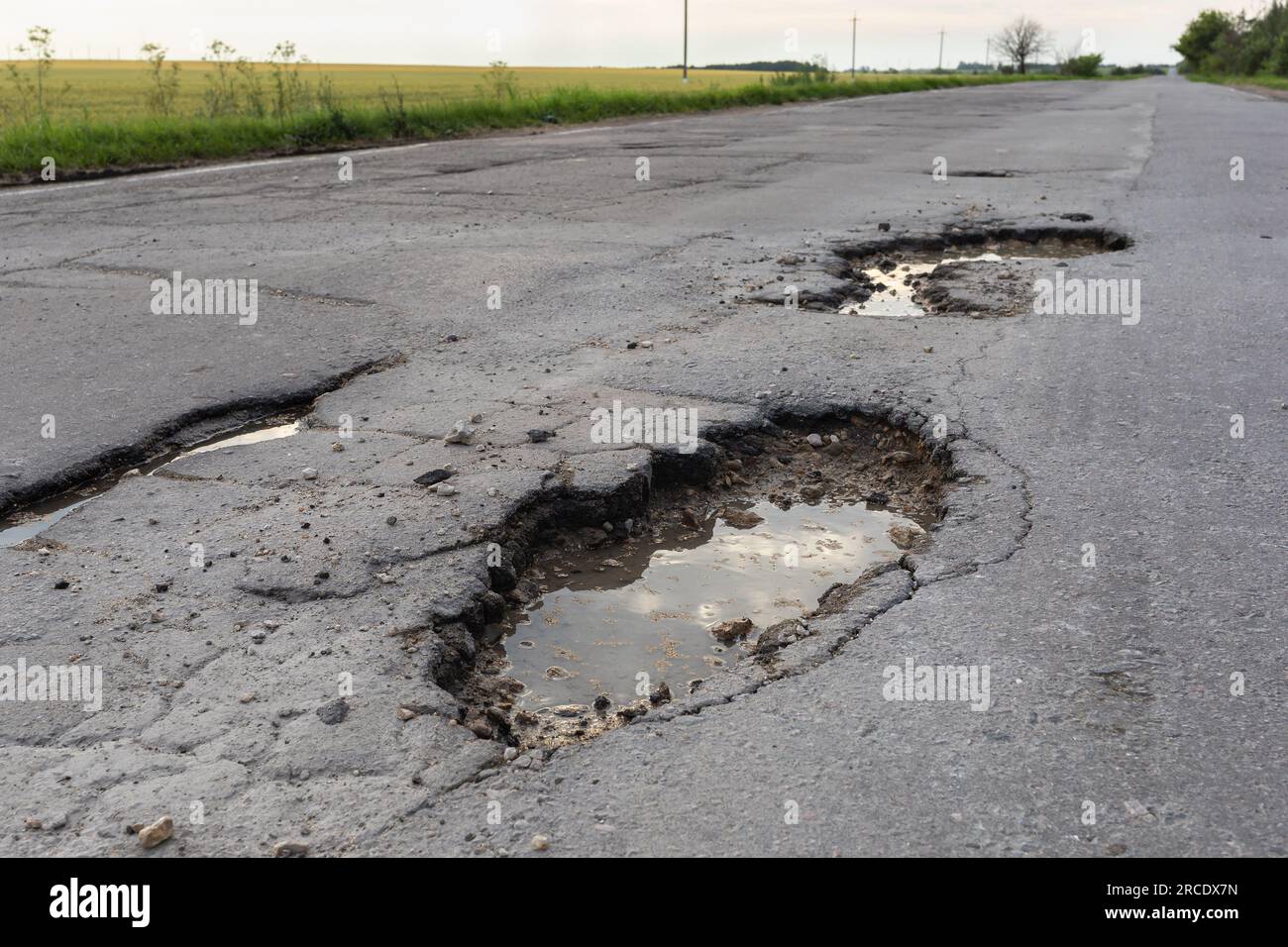 Pozzi sulla strada asfaltata, un concetto sul tema delle cattive strade Foto Stock