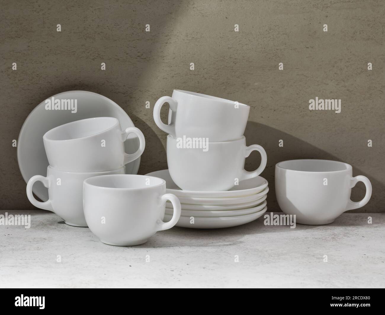 Un set di piatti in ceramica bianca sul tavolo, tazze e piattini per tè o caffè Foto Stock
