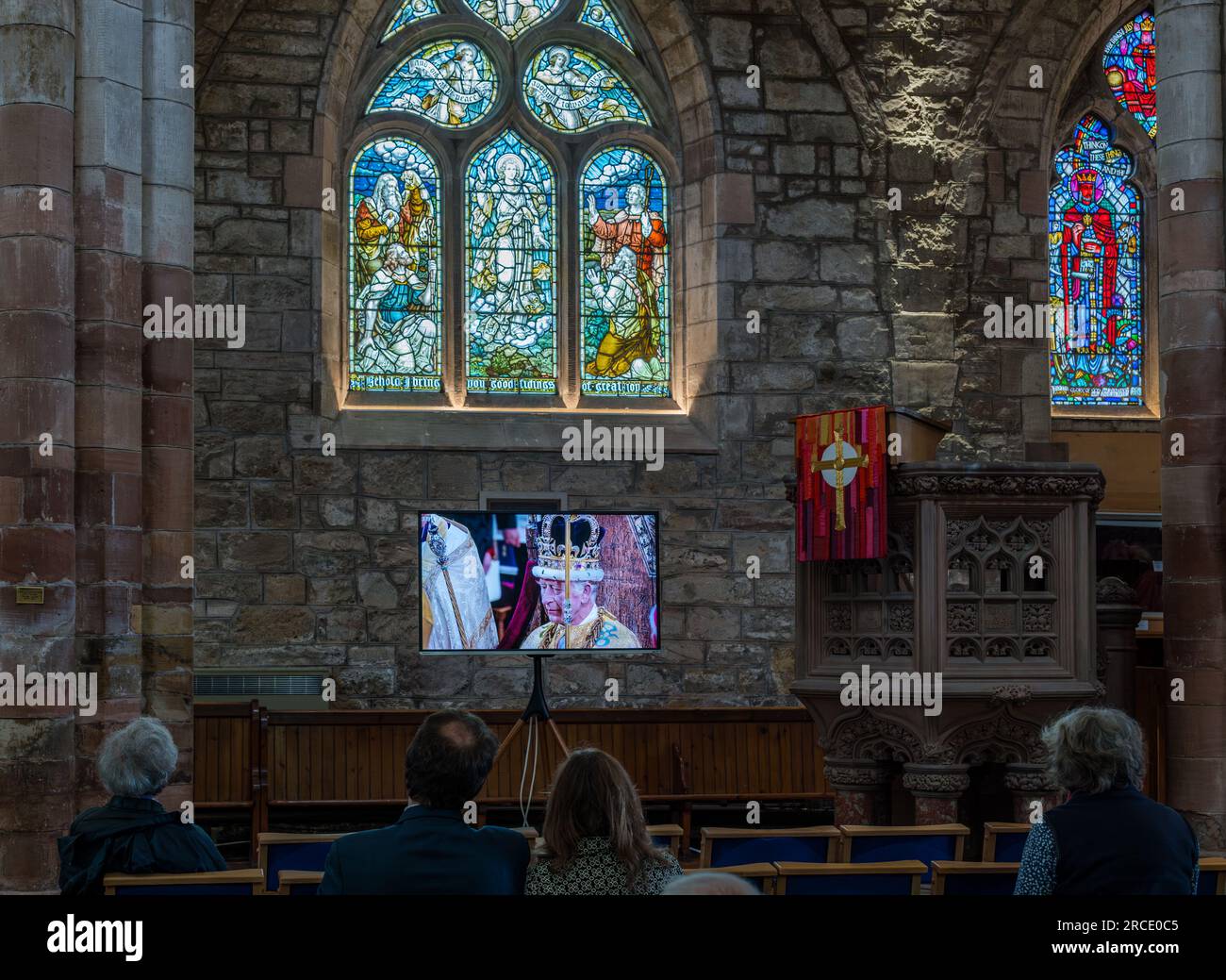 Persone che guardano l'incoronazione di re Carlo III sullo schermo TV, St Mary's Parish Church, Haddington, East Lothian, Scozia, Regno Unito Foto Stock