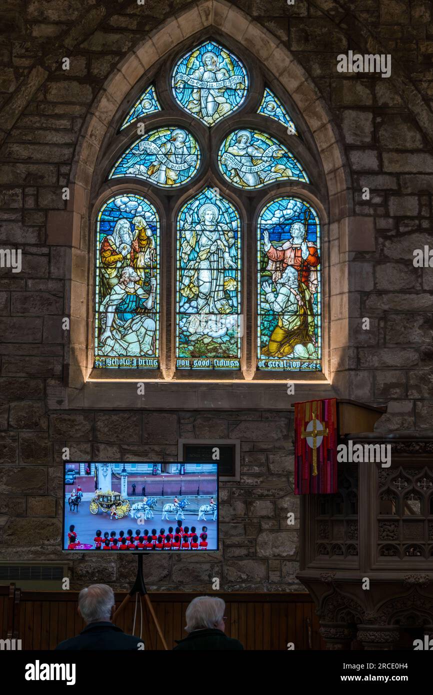 Persone che guardano l'incoronazione di re Carlo III sullo schermo televisivo con carrozza trainata da cavalli d'oro, St Mary's Parish Church, Haddington, East Lothian, Scozia, Regno Unito Foto Stock