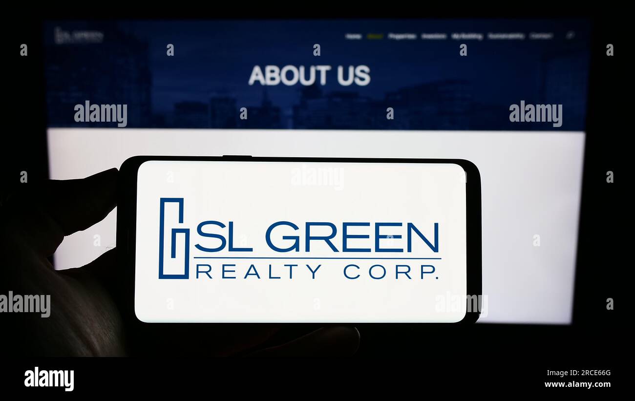 Persona che possiede uno smartphone con il logo della società immobiliare statunitense SL Green Realty Corp. Sullo schermo di fronte al sito Web. Concentrarsi sul display del telefono. Foto Stock