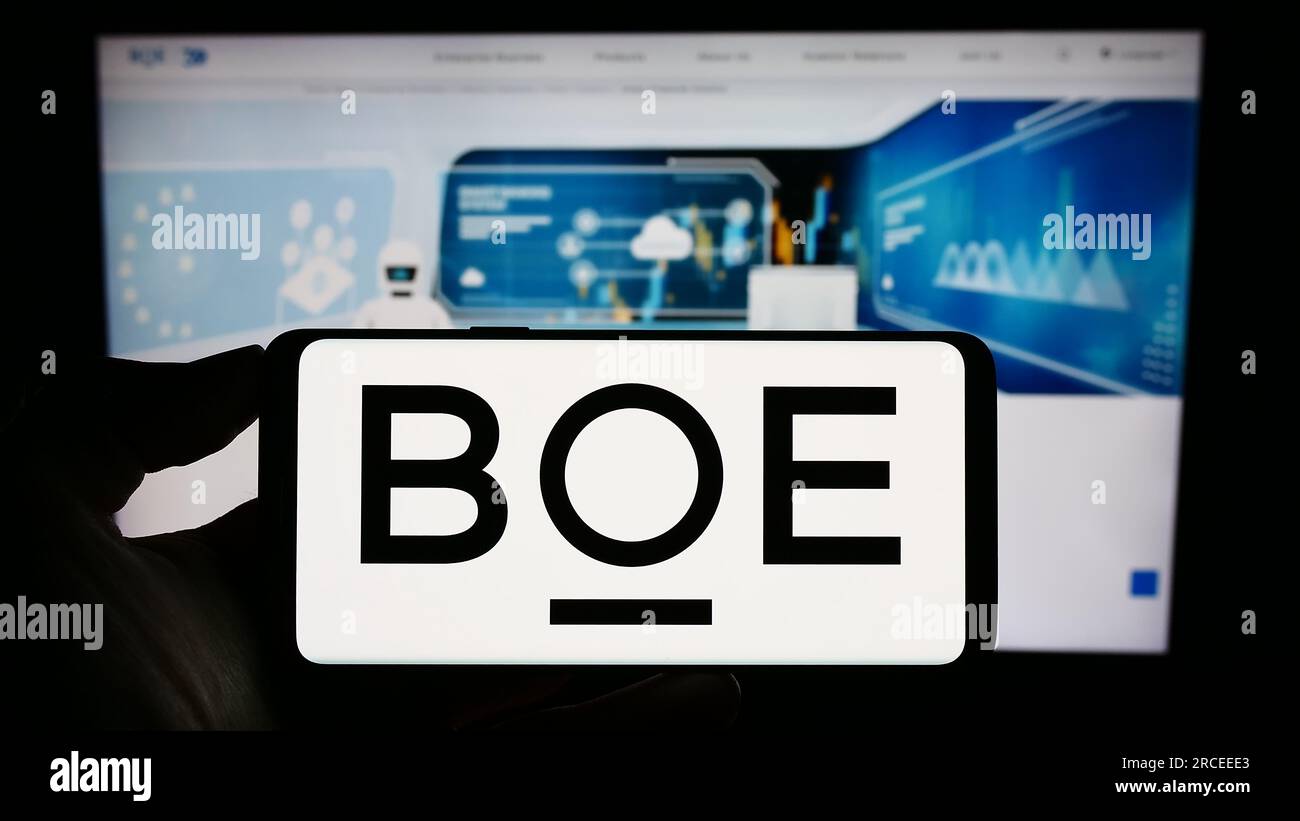 Persona che possiede un telefono cellulare con il logo della società cinese BOE Technology Group Co. Ltd. Sullo schermo davanti alla pagina Web. Concentrarsi sul display del telefono. Foto Stock