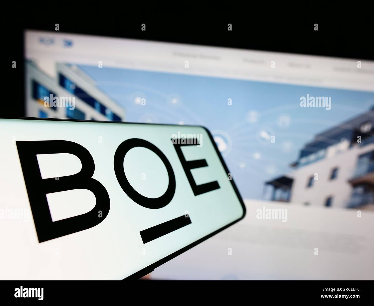 Cellulare con logo della società cinese BOE Technology Group Co. Ltd. Sullo schermo davanti al sito Web. Mettere a fuoco il display centrale sinistro del telefono. Foto Stock