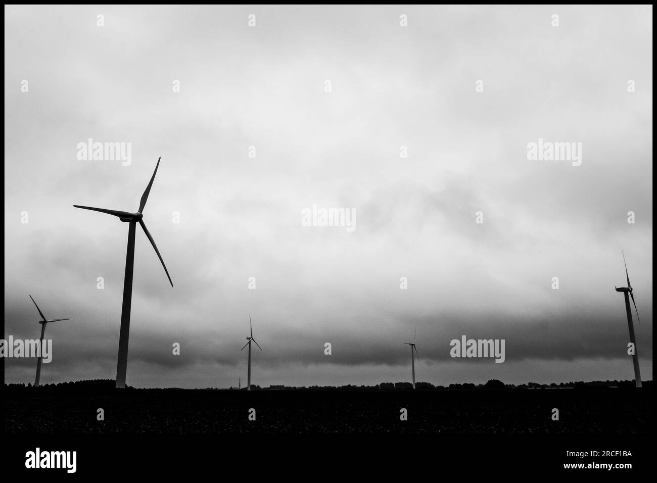 Parc eolien au milieu des champs dans les Rural Wallones sous un ciel nuageux menacant | Faro eolico nel mezzo dei campi sotto un teathenin Foto Stock