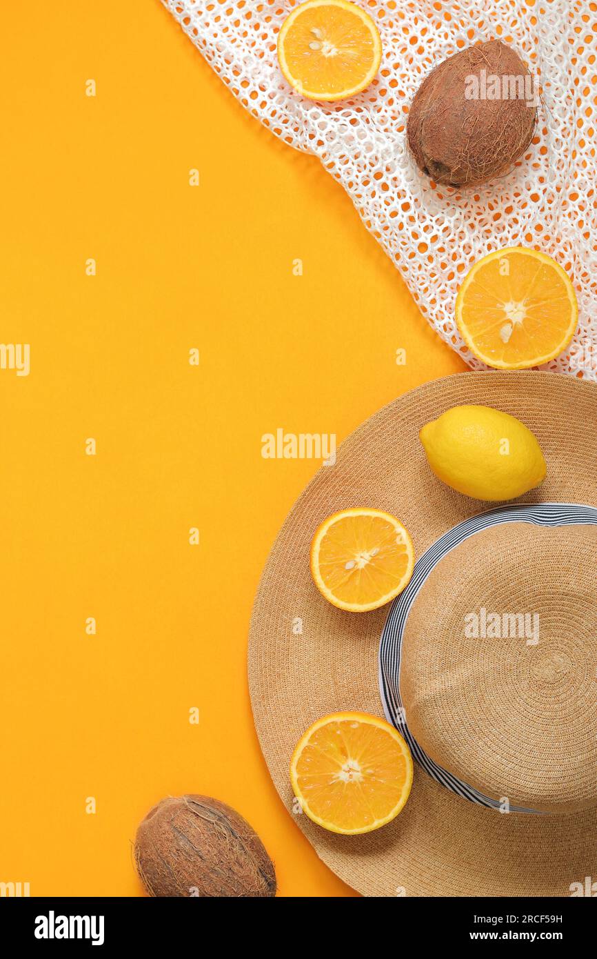 Sfondo giallo brillante estivo con cappello, borsa in mesh, arance, limone e cocco. Vista dall'alto, base piatta Foto Stock