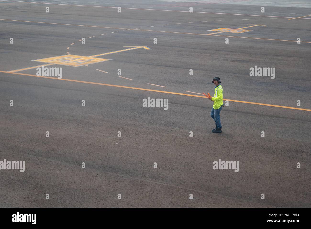 Medellin, Antioquia, Colombia - 23 ottobre 2022: Controller del traffico aereo maschile con gilet giallo fluorescente e Blue Jeans fissa l'obiettivo Walking D. Foto Stock