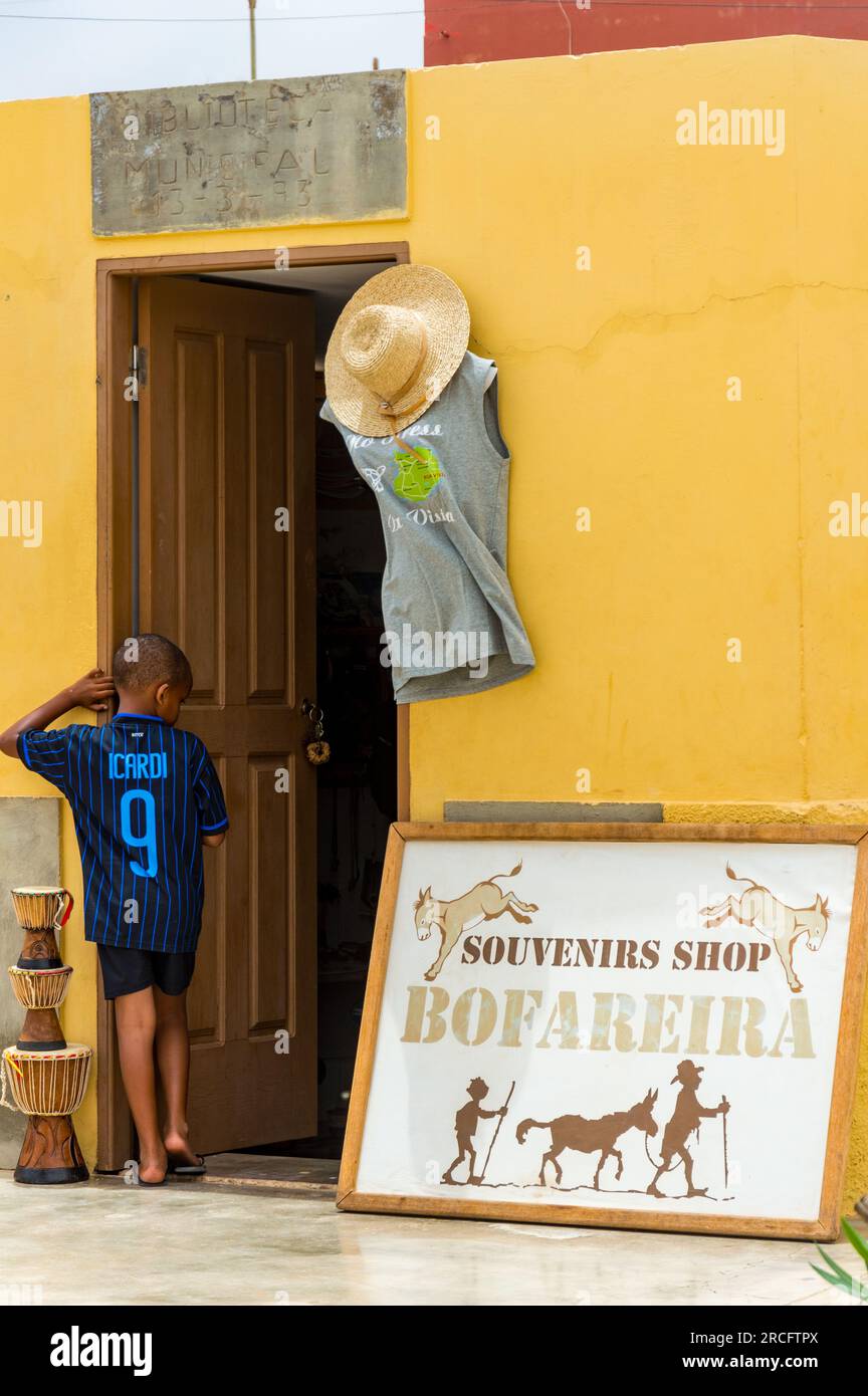 Un giovane ragazzo africano in piedi fuori da un negozio di souvenir a Bofareira, Boa Vista, Capo Verde, Africa Foto Stock