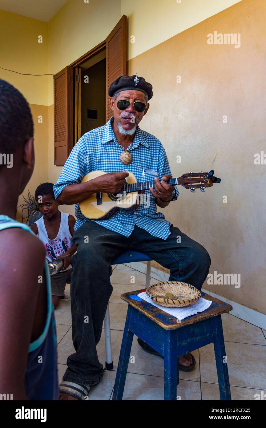Un uomo africano che gioca l'Ukulele ad alcuni bambini, Boa Vista, Capo Verde, Africa Foto Stock