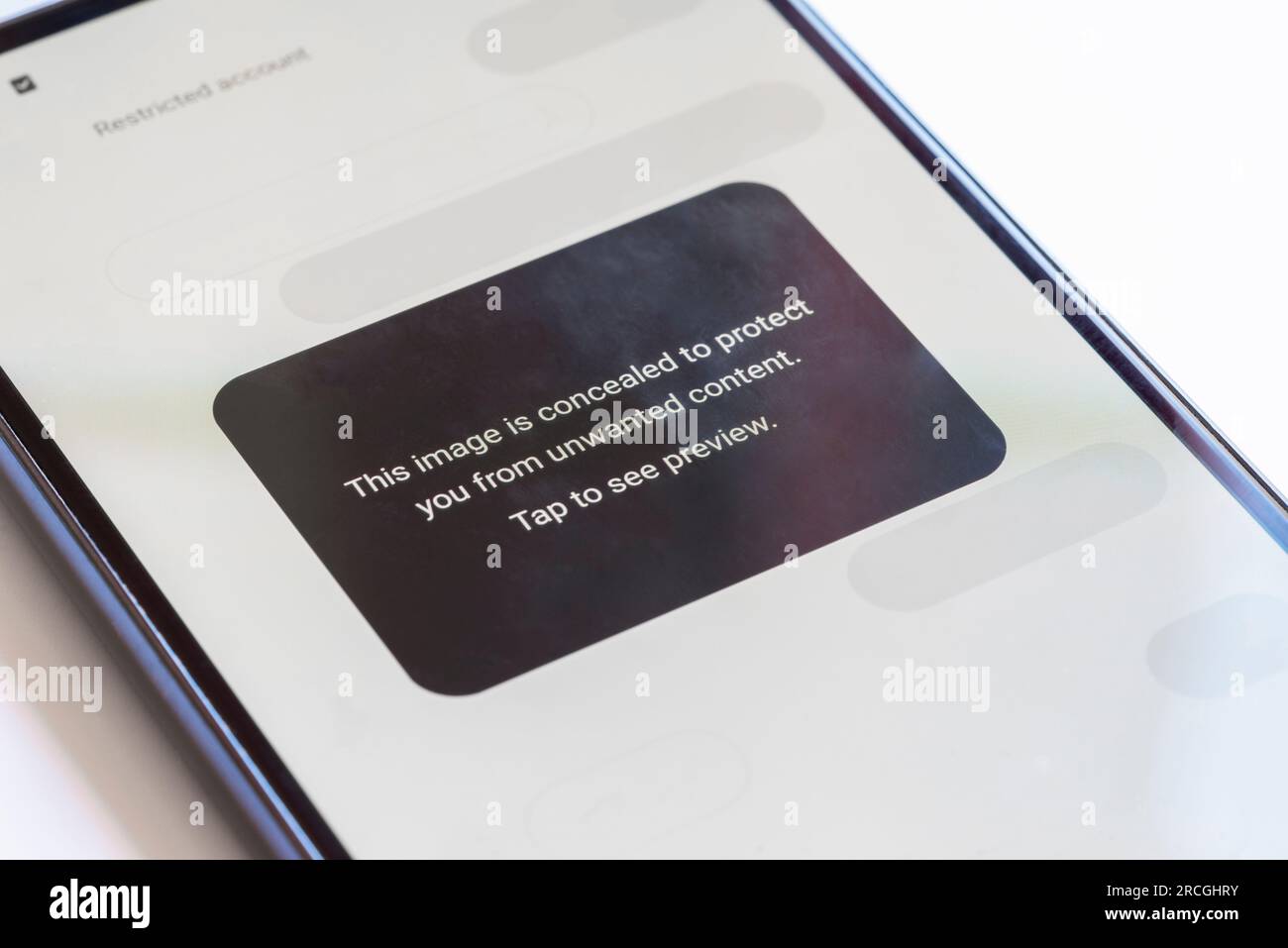 "Questa immagine è nascosta per proteggerti da contenuti indesiderati" avvertendo l'utente di contenuti dannosi sui social media visualizzati su un telefono cellulare, Regno Unito Foto Stock