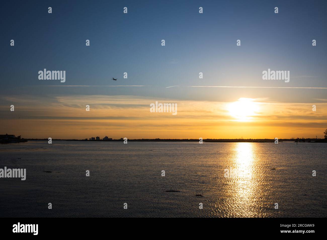 Paesaggio che raffigura il sole che tramonta a Long Island, New York, con le unghie nel cielo, gli alberi sullo sfondo e il riflesso dell'oceano. Foto Stock