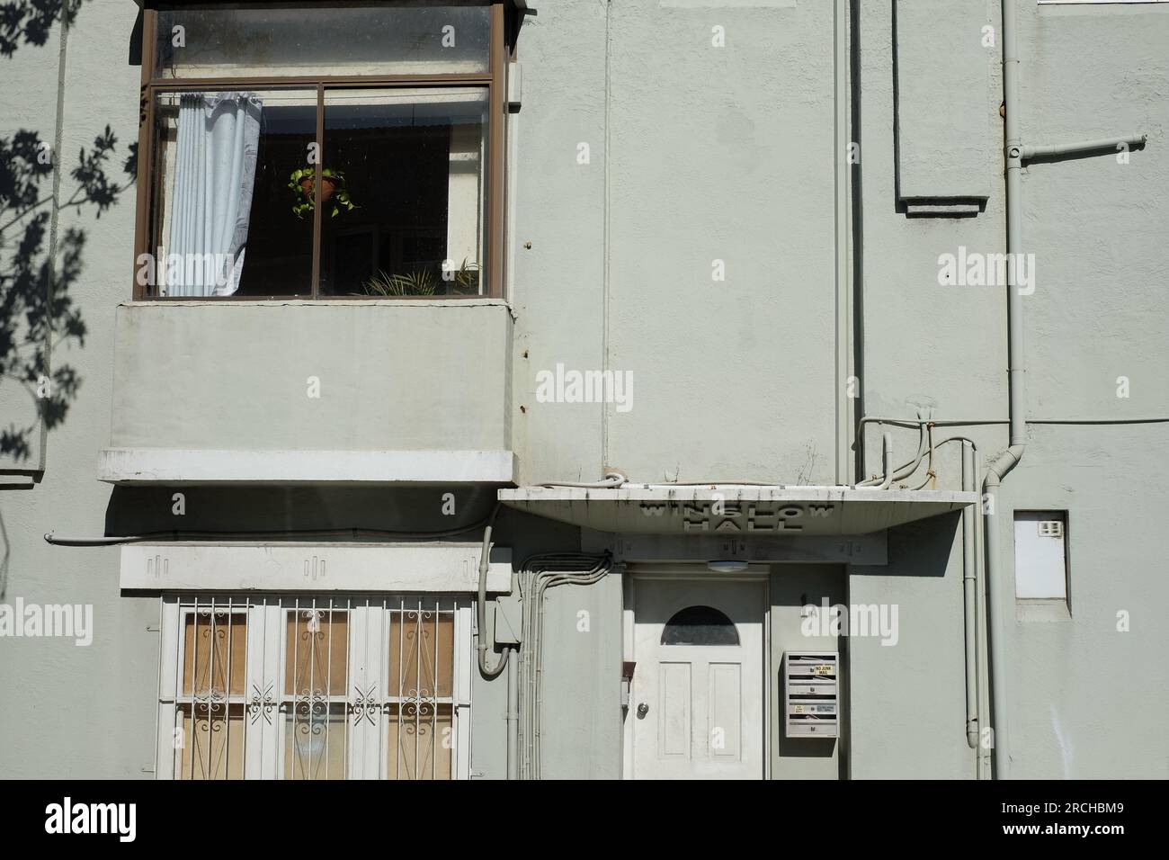 Vista dettagliata dell'ingresso agli appartamenti Winslow Hall, una tenda in cemento con il nome in rilievo sulla tenda. Sportello, cassetta postale Windows vecchia e nuova Foto Stock