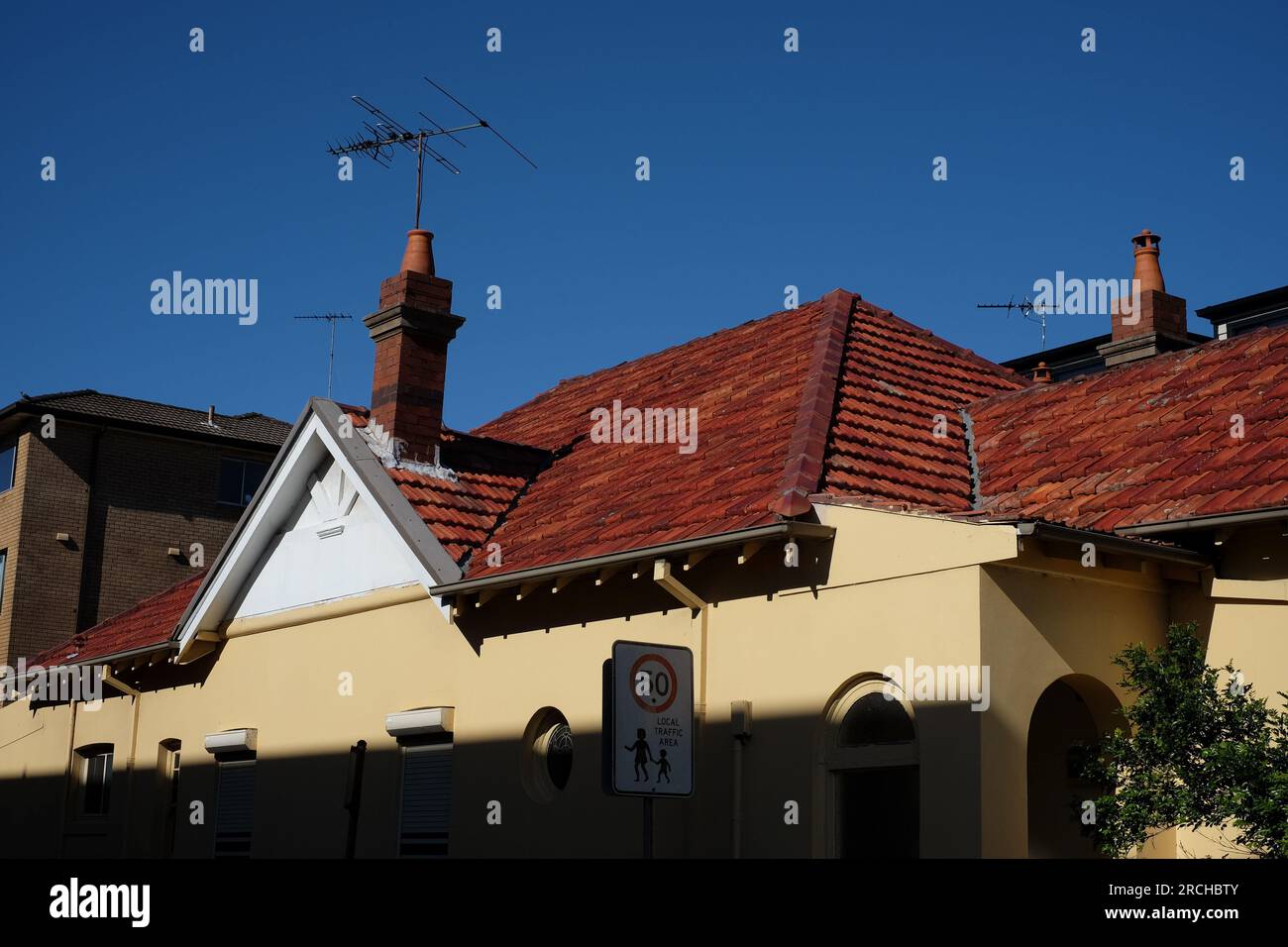 Il tetto a capanna con tegole rosse di una federazione su Bondi Road, parete laterale gialla in ombra profonda contro un cielo blu profondo Bondi, New South Wales Foto Stock