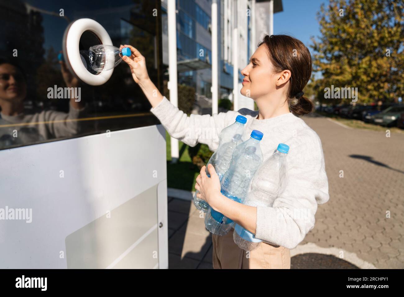 La donna usa una macchina self-service per ricevere bottiglie e lattine di plastica usate in una strada cittadina. Foto Stock