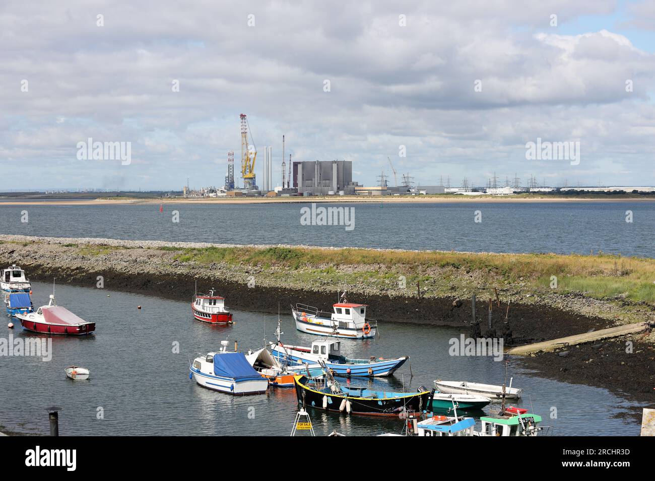 La vista dal Paddy’s Hole verso la centrale nucleare di Hartlepool e la gigantesca gru della nave di supporto offshore per l’industria eolica, Vo Foto Stock