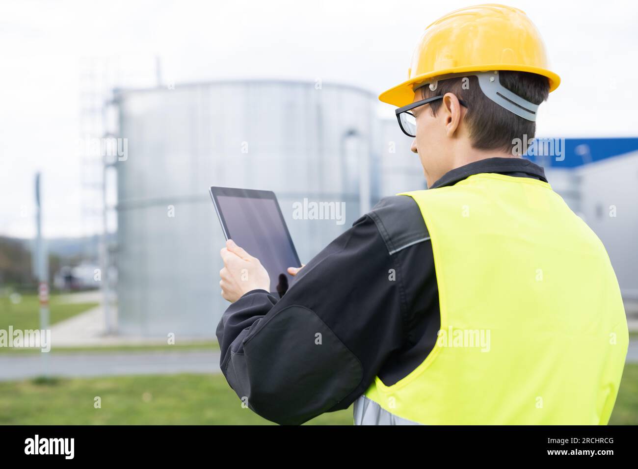 Ingegnere con tablet digitale su uno sfondo di serbatoi di gas. Foto Stock