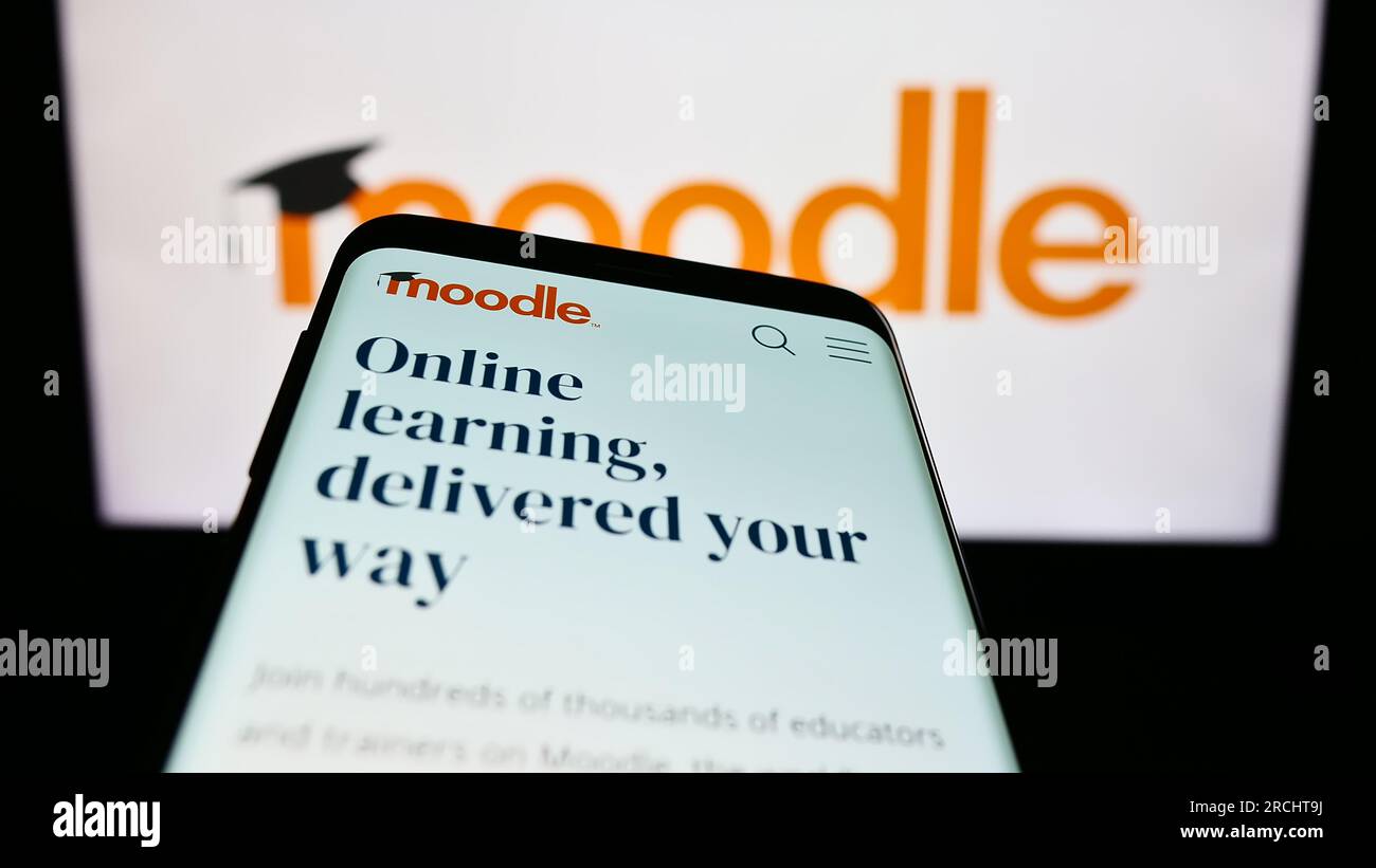 Smartphone con sito Web della piattaforma di apprendimento Moodle sullo schermo davanti al logo. Mettere a fuoco in alto a sinistra sul display del telefono. Foto Stock