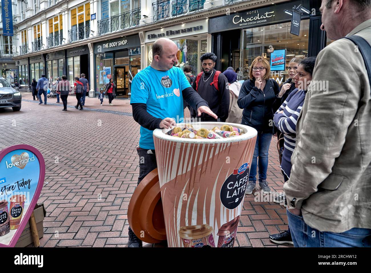 Promozione caffè latte con assaggi gratuiti consegnati ai passanti di New Street, Birmingham, Inghilterra, Regno Unito Foto Stock