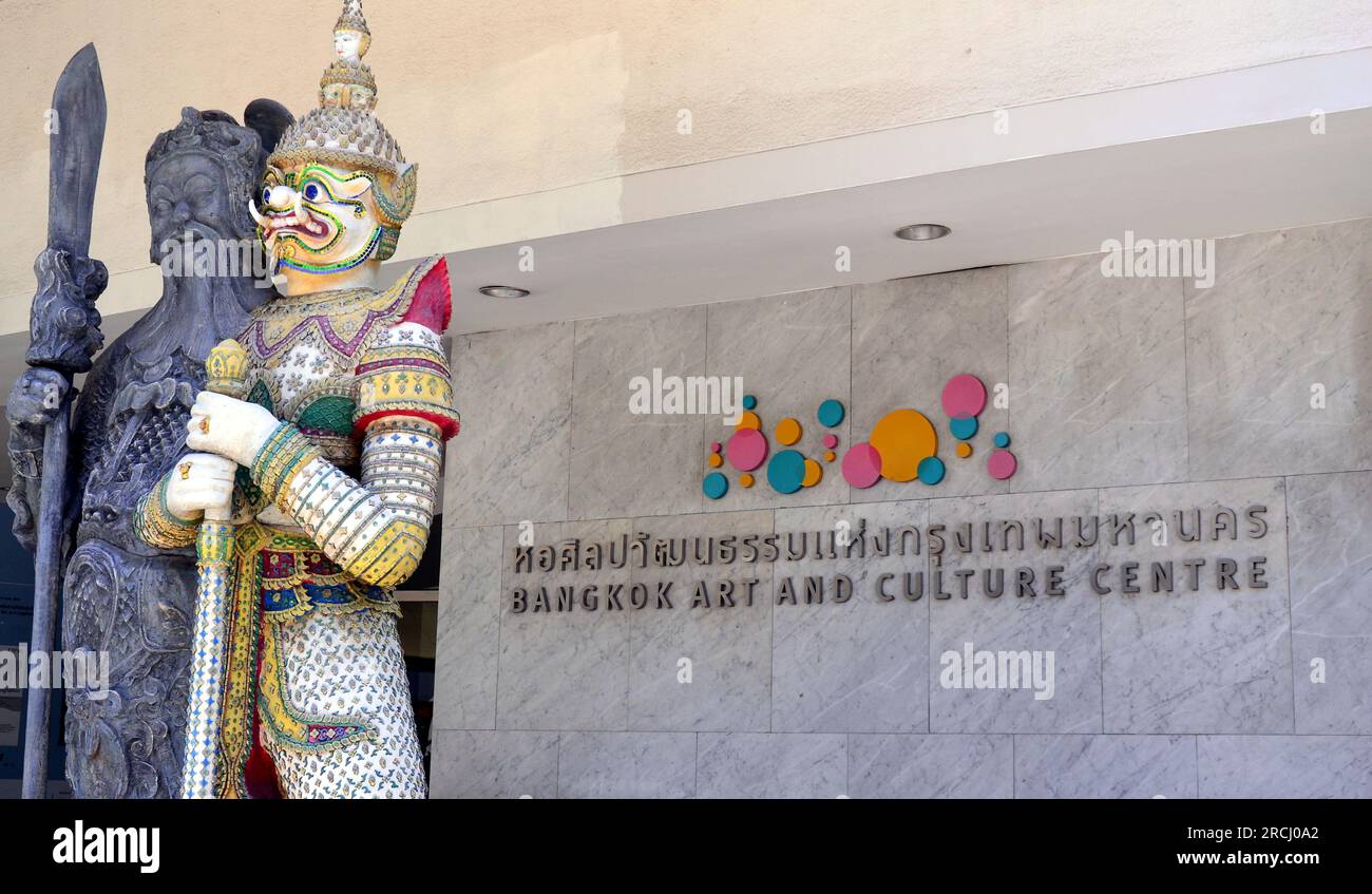 L'esterno del Bangkok Art and Culture Centre, con statue guardiane, centro d'arte contemporanea a Bangkok, Thailandia. Arte, musica, teatro, cinema, design ed eventi culturali ed educativi si svolgono nei suoi spazi espositivi e di spettacolo. Il centro comprende caffetterie, gallerie d'arte commerciali, librerie, negozi di artigianato e una biblioteca d'arte. Il 14 luglio, in serata, una protesta dei sostenitori del Move Forward Party (MFP) ha avuto luogo all'esterno. Il 13 luglio Pita Limjaroenrat ha perso il voto in Parlamento per diventare primo ministro, nonostante il suo partito abbia vinto il maggior numero di voti nelle ultime elezioni. Foto Stock