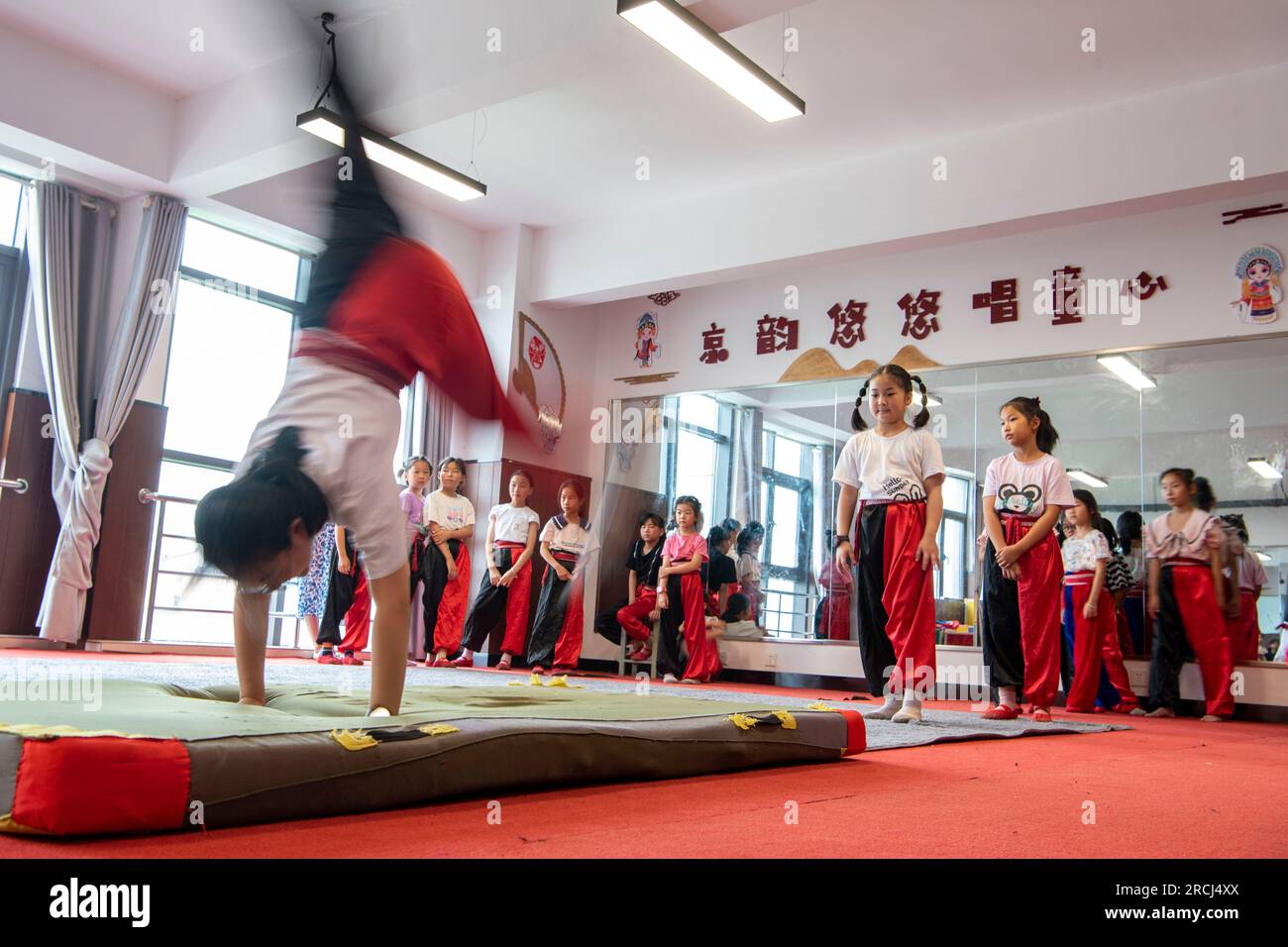 HAI'AN, CINA - 15 LUGLIO 2023 - i bambini di una scuola elementare club dell'Opera di Pechino praticano le abilità di base dello spettacolo dell'Opera di Pechino sotto la guida Foto Stock