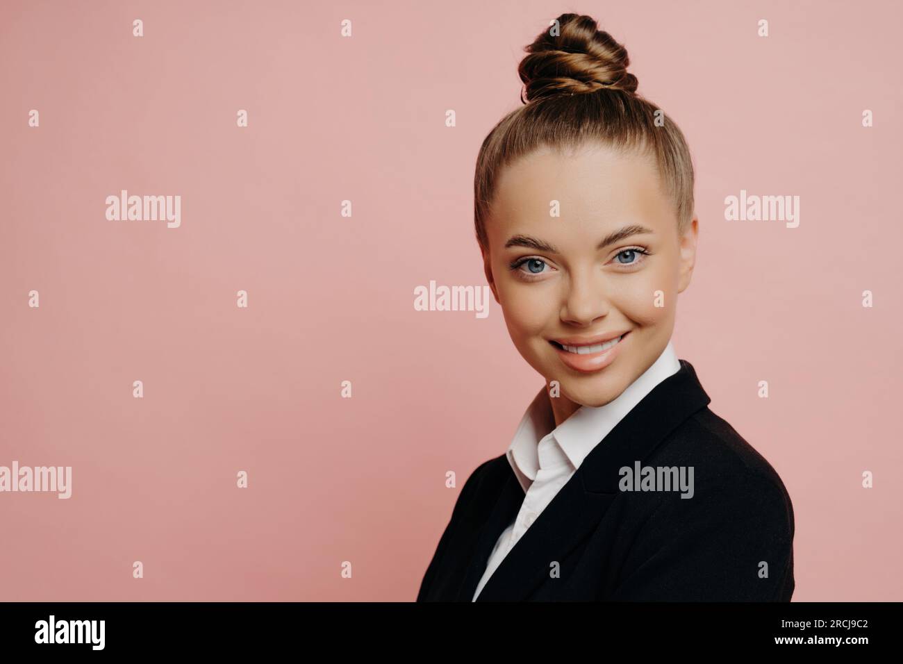 Portirat di allegro felice impiegato di ufficio femminile in vestito scuro con i capelli in panda che è notificato circa la sua promozione, con il sorriso bello in piedi lateralmente Foto Stock