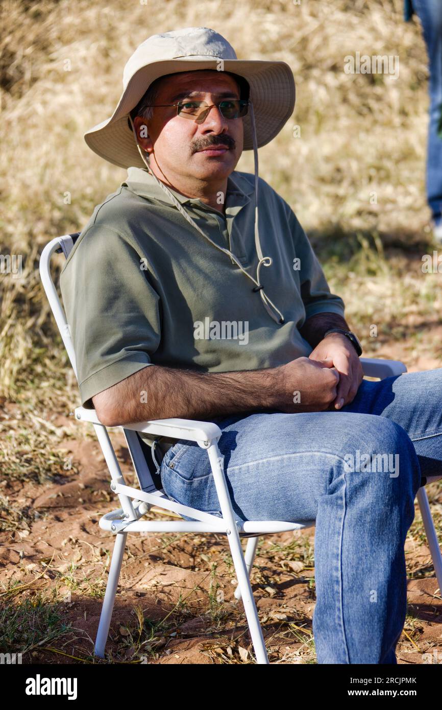 adulto arabo seduto sulla sedia durante una pausa in un safari africano nel bush Foto Stock