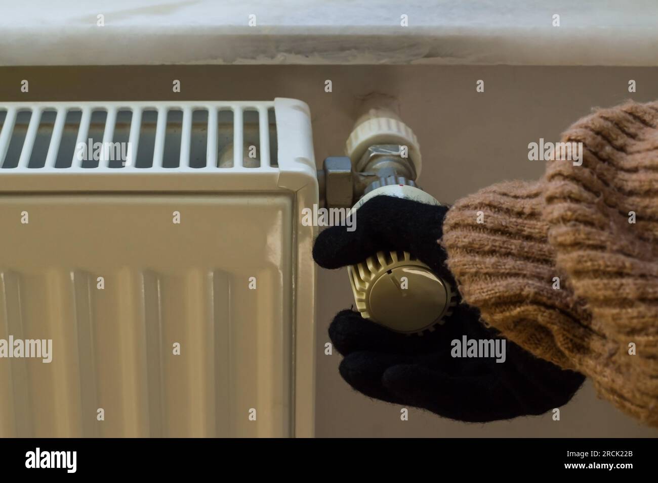 Mano nei guanti e maglione invernale spesso controlla la valvola del gas naturale. Foto Stock