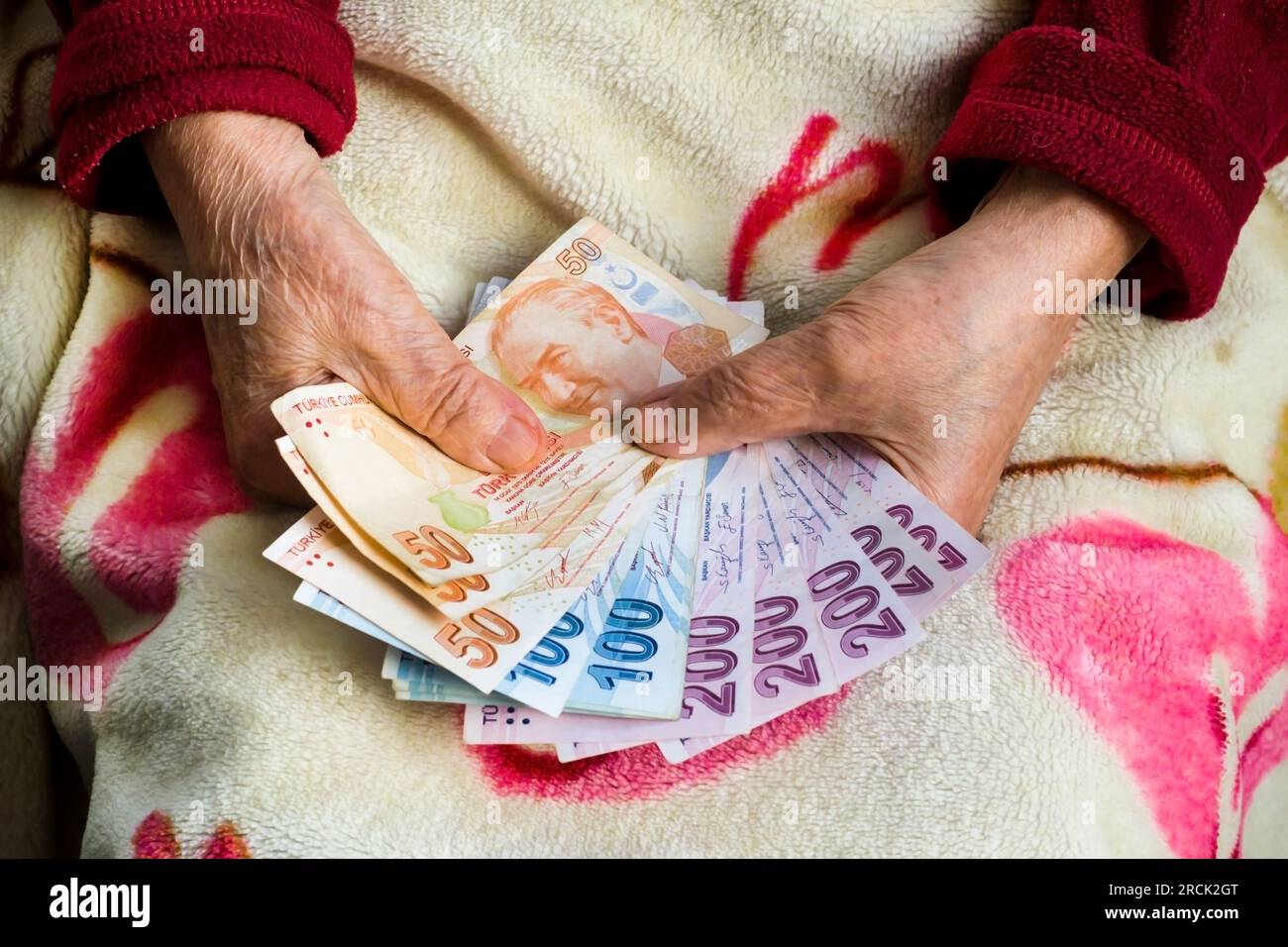 Mani di un adulto che tiene delle banconote turche sulla sua coperta di lana. Concetto di pensione Foto Stock