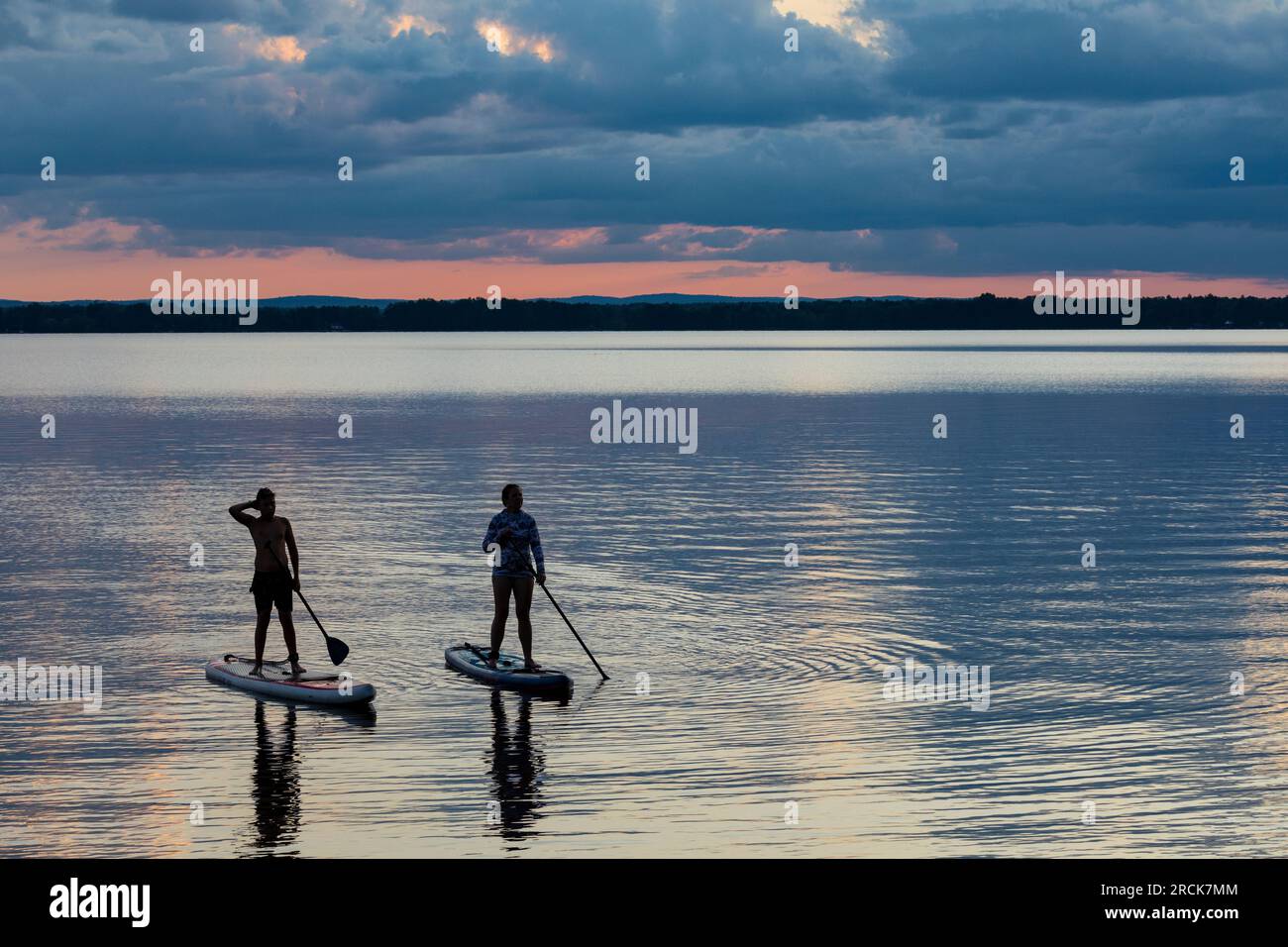 Donna e ragazzo in paddle board al tramonto nel lago. Golden Lake Ontario Canada Foto Stock