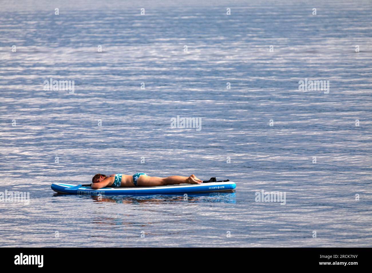 Donna che si rilassa a bordo di una tavola da paddle nelle giornate di sole. Golden Lake Ontario Canada Foto Stock