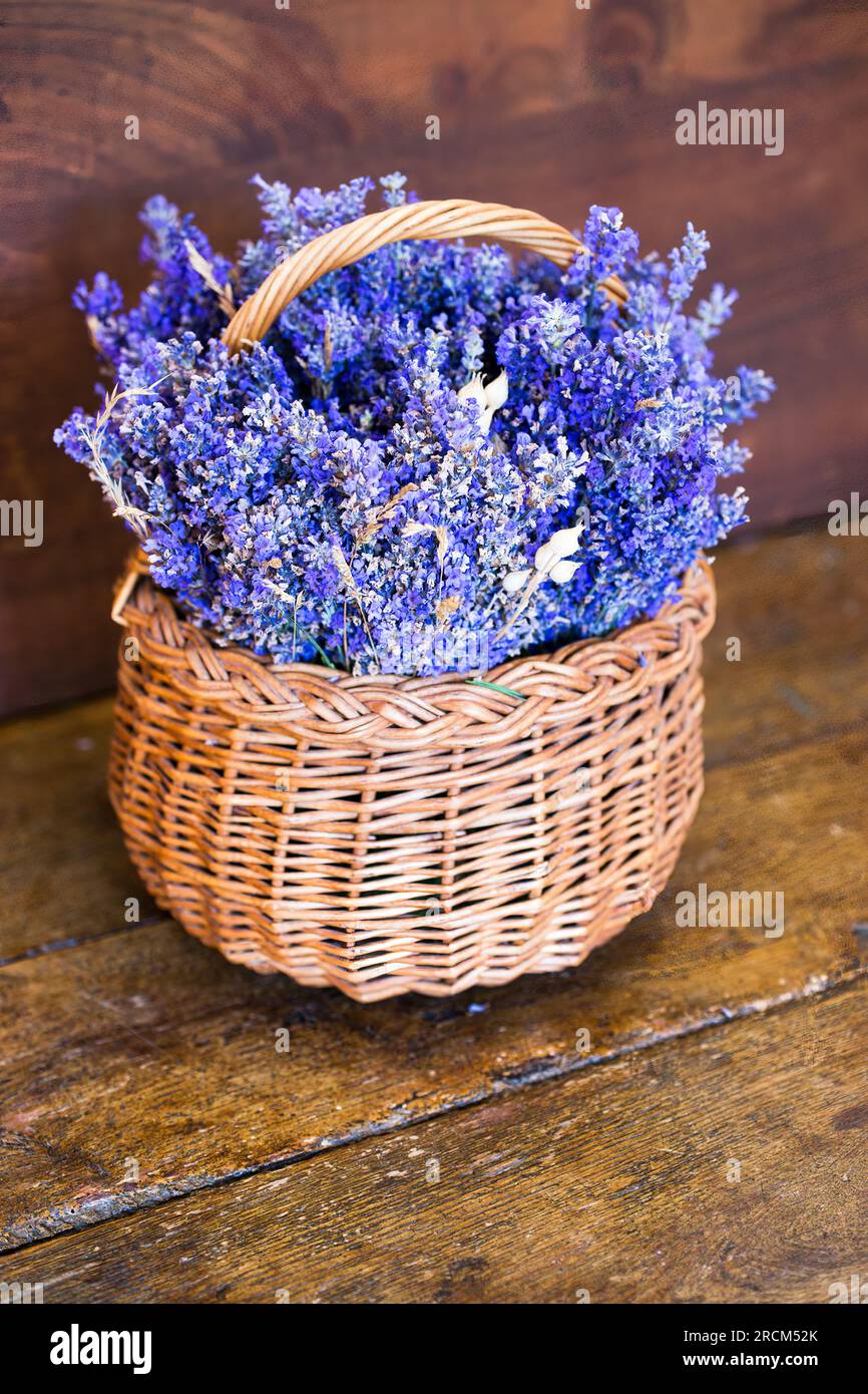 Lavanda fresca (Lavandula angustifolia) in un cestino di vimini su un tavolo di legno Foto Stock