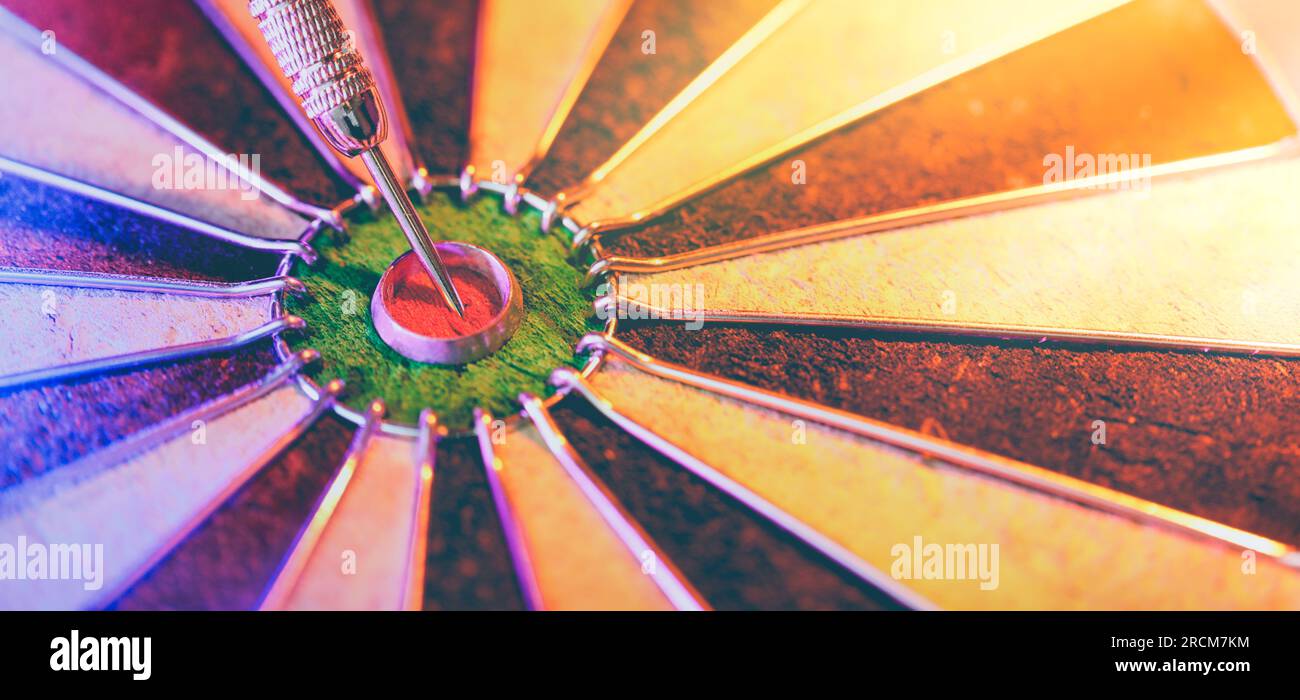 DART board che mostra un dardo che colpisce il torello centrale. Concetto di successo, definizione e raggiungimento di obiettivi mirati e ricerca della perfezione. Foto Stock