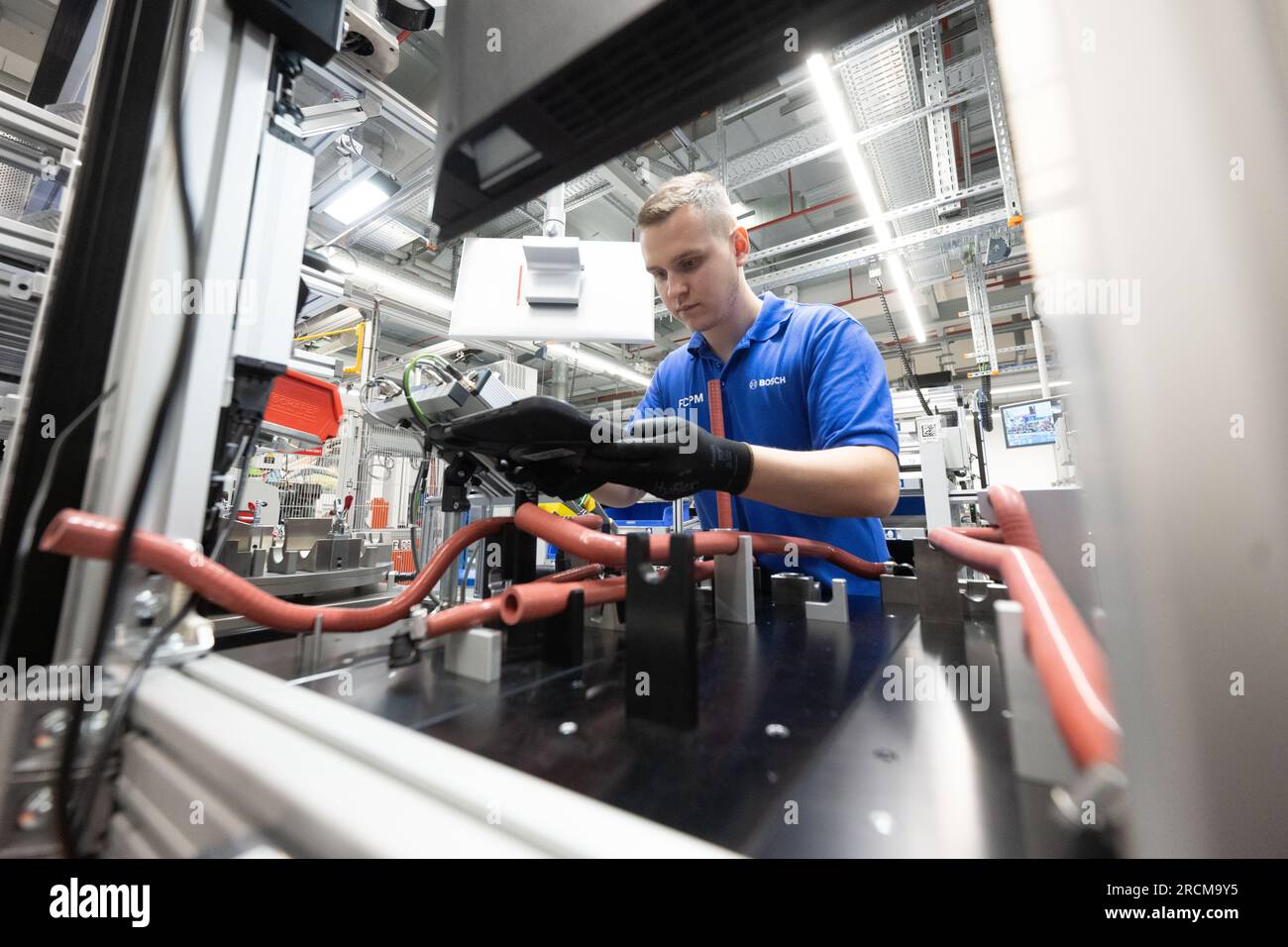 Stoccarda, Germania. 12 luglio 2023. Un dipendente della Robert Bosch GmbH controlla le fascette stringitubo di un sistema di azionamento delle celle a combustibile per generare elettricità dall'idrogeno nei veicoli durante la produzione. Il cosiddetto modulo di alimentazione delle celle a combustibile (FCPM) viene utilizzato principalmente nei veicoli commerciali e nelle applicazioni a lunga distanza. L'FCPM è costituito da una o due pile di celle a combustibile e da altri componenti necessari per azionare le pile. Crediti: Marijan Murat/dpa/Alamy Live News Foto Stock