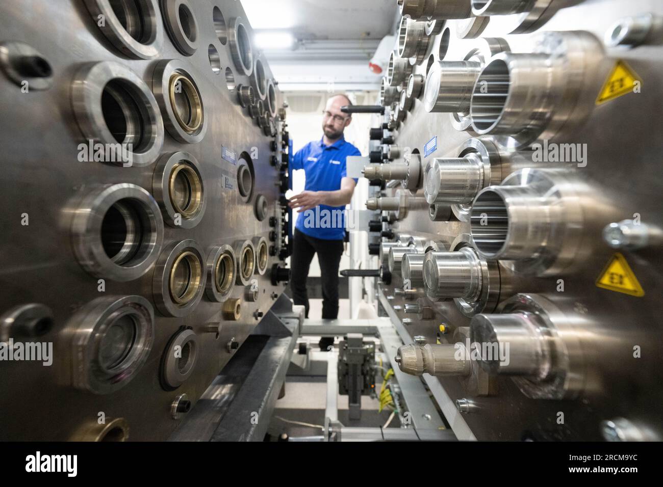 Stoccarda, Germania. 12 luglio 2023. Un dipendente della Robert Bosch GmbH prepara un banco di prova per il collaudo di fine linea di un sistema di azionamento a celle a combustibile per la generazione di elettricità dall'idrogeno nei veicoli. Il cosiddetto modulo di alimentazione delle celle a combustibile (FCPM) viene utilizzato principalmente nei veicoli commerciali e nelle applicazioni a lunga distanza. L'FCPM è costituito da una o due pile di celle a combustibile e da altri componenti necessari per azionare le pile. Crediti: Marijan Murat/dpa/Alamy Live News Foto Stock