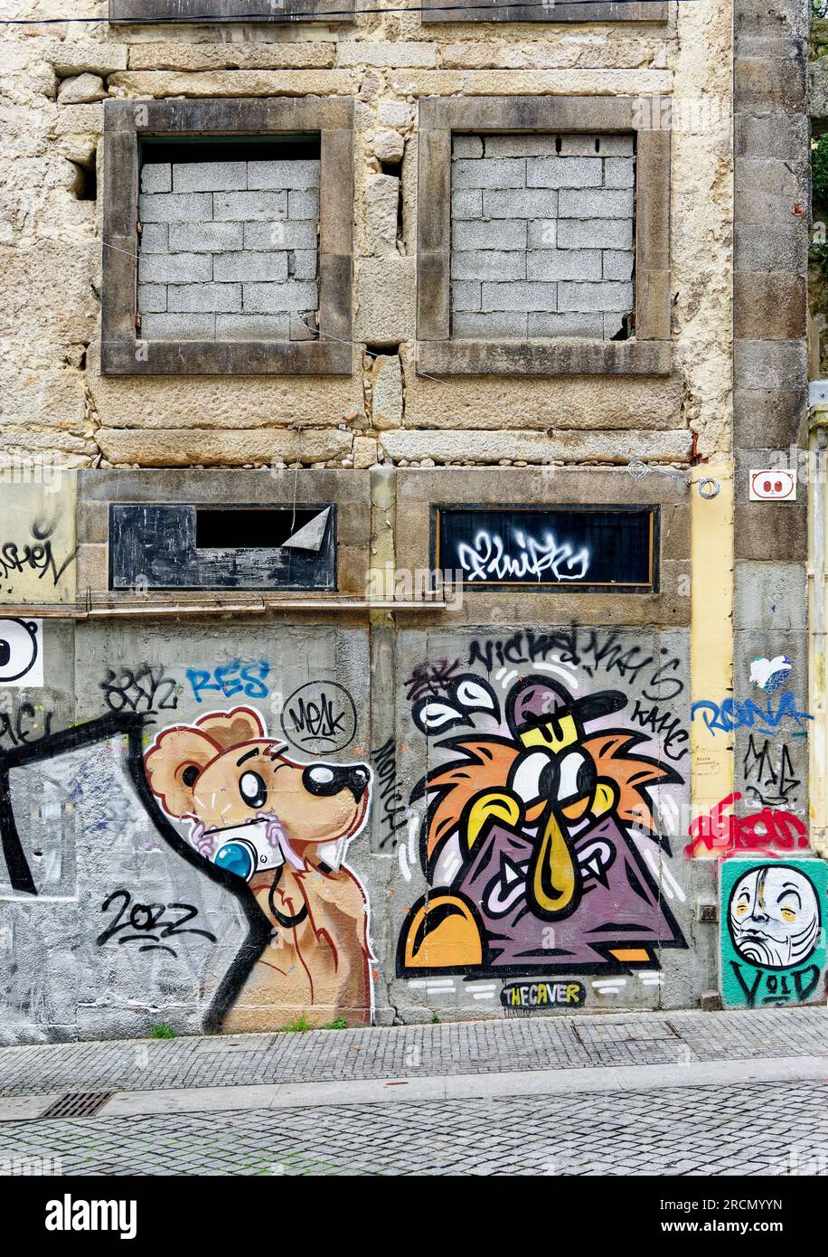 Finestre in mattoni e graffiti su un edificio vuoto abbandonato nel centro di Porto, degrado urbano. Foto Stock