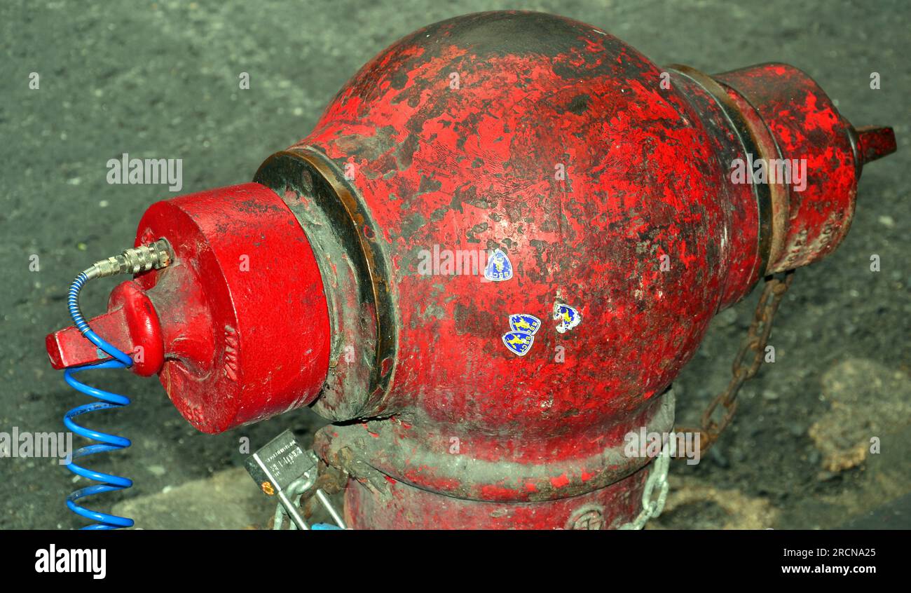 Un vecchio idrante rosso, graffiato, dall'aspetto malandato, pronto a fornire acqua ai vigili del fuoco in una strada a Bangkok, Thailandia Foto Stock