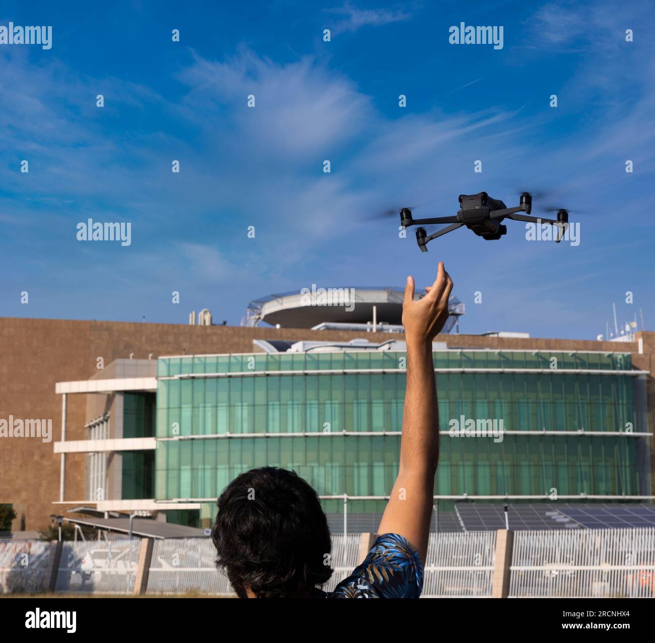 Pilota di droni che cattura il drone all'atterraggio, giovane uomo all'aperto che gestisce un UAV che fa un'indagine Foto Stock
