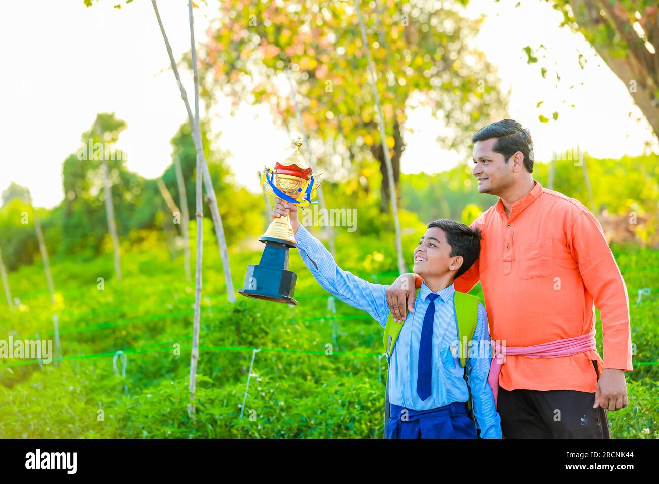 Figlio che mostra trofeo suo padre , felice contadino e figlio , agricoltura indiana Foto Stock